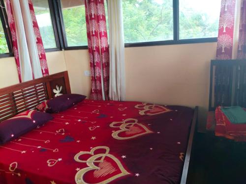 Un dormitorio con una colcha roja con corazones. en Lake View Homestay Kundara, 