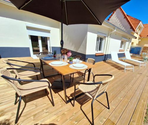 a wooden deck with a table and chairs with an umbrella at La Casa César Maison 10 couchages in Bracquemont