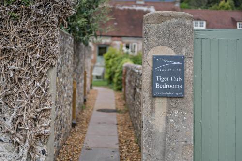 a sign on a stone fence with a tree club bathroom at Cub Bedroom Five in Eastdean