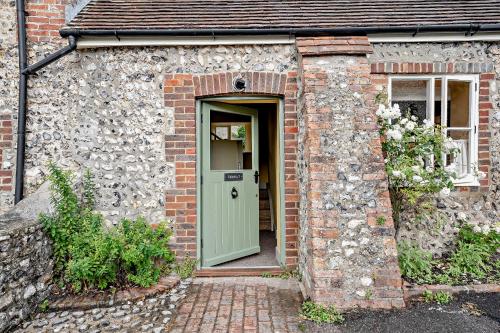 a brick house with a green door in front at Cub Bedroom Six in Eastdean