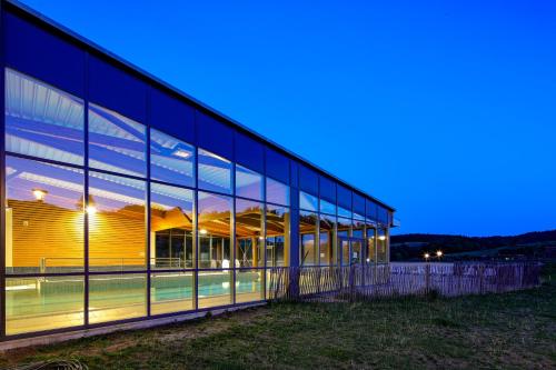 a large building with glass windows at night at Village Vacances Passion Le Cezallier in Ardes-sur-Couze