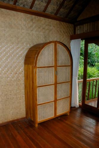 an empty room with a wooden door and a window at Nishiyama Wooden House in Ambengan