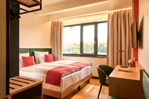 Una habitación de hotel con una cama, un escritorio y una ventana. en Hotel Morgenroth, en Bad Blankenburg