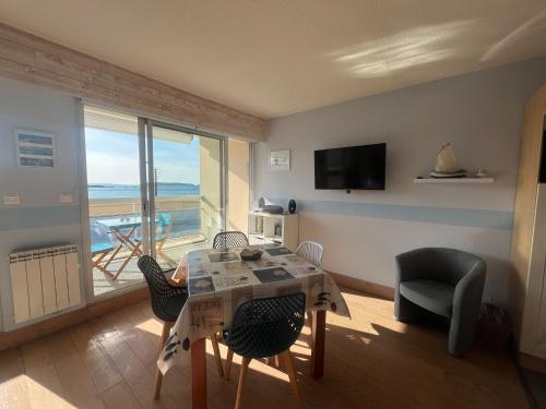 a living room with a table and chairs and a balcony at Studio Vue imprenable sur la Mer et les 7 Iles in Trévou-Tréguignec