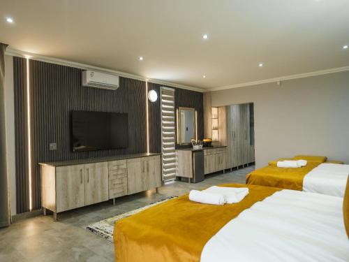 a hotel room with two beds and a flat screen tv at Humdani Safaris Free State in Virginia
