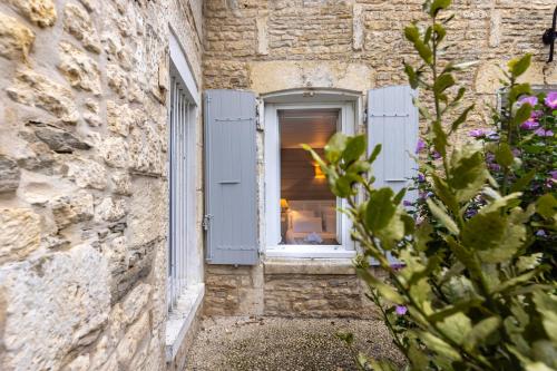 a window in a stone building with blue shutters at Hôtel Le Square in Saint-Pierre-dʼOléron