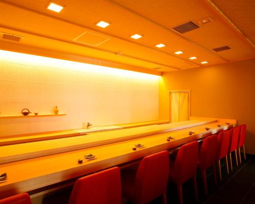 a conference room with red chairs and a long table at Hotel Bestland in Tsukuba