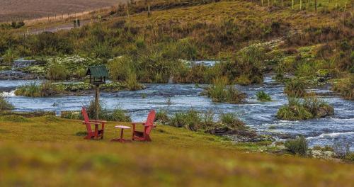 two red chairs and a table next to a river at Parador Cambará do Sul in Cambara do Sul