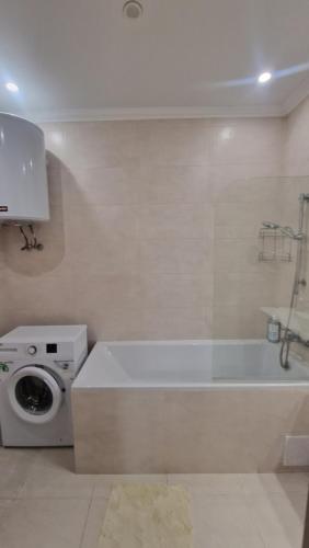 ein Badezimmer mit einer Badewanne und einer Waschmaschine in der Unterkunft 1 комн квартира в Кадоре на Таирова in Odessa