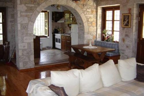 Leonidio Stone House في Pragmatevtís: غرفة معيشة مع أريكة بيضاء وطاولة