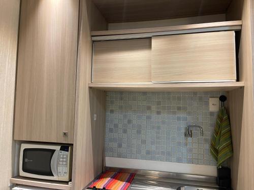 uma cozinha com um micro-ondas, um lavatório e um balcão em Requinte Flats Beach em Cabo Frio