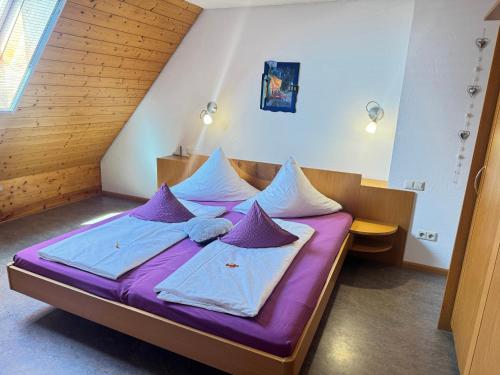 un letto in una stanza con cuscini viola e bianchi di Ferienwohnung- Stabhalterhof a Freiamt