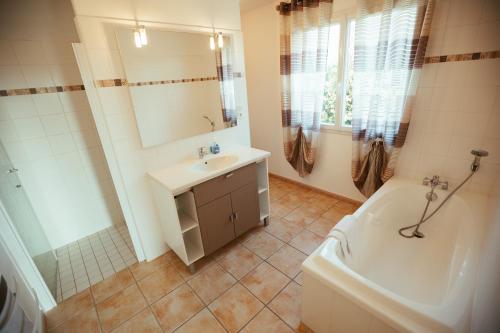 a bathroom with a sink and a tub and a toilet and a mirror at Les Villas de Perret in Joyeuse