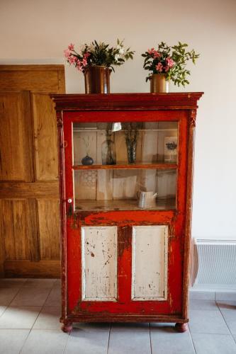 an old red cabinet with flowers on top of it at Les Villas de Perret in Joyeuse