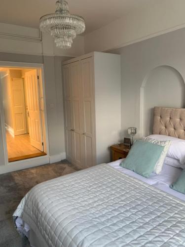 a bedroom with a large white bed with a chandelier at The Annexe Westbury House in Great Dunmow