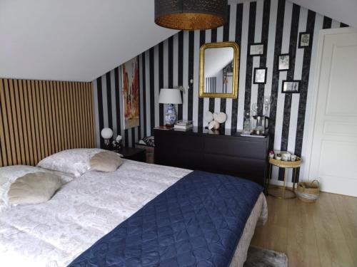 a bedroom with a large bed and a mirror at CHEZ HÉLÈNE in Saint-Coulomb