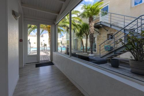 an empty balcony with glass doors and palm trees at Hôtel Le Square in Saint-Pierre-dʼOléron