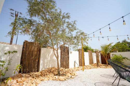 a tree in a yard next to a fence at Maison Miraj Hostel in Muscat