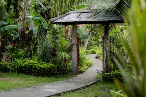 a walkway in a garden with a gazebo at Nishiyama Wooden House in Ambengan