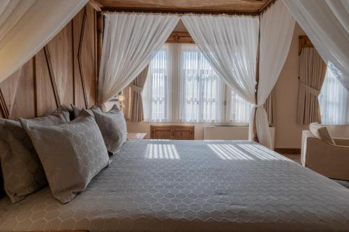 a bedroom with a canopy bed with pillows at Asmalı Konak Cave Suites in Urgup