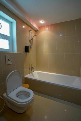 a bathroom with a toilet and a bath tub at Maison Miraj Hostel in Muscat