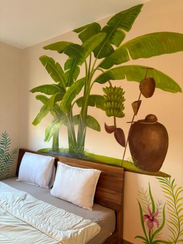 a bedroom with a bed with a plant mural on the wall at Thien Hai Home in Quy Nhon