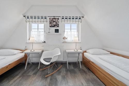 BrösumにあるLille Dröm Reetdachhaus Lille Drömのベッド2台、デスク、椅子が備わる客室です。