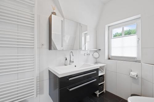 BrösumにあるLille Dröm Reetdachhaus Lille Drömの洗面台と鏡のある白いバスルーム