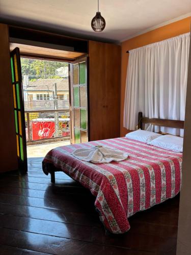 a bedroom with a bed and a large window at Pousada da Brigida in Campos do Jordão