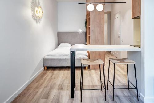 Zimmer mit einem Tisch, 2 Hockern und einem Bett in der Unterkunft Domillion Studio Modern Old Town Retreat So1b in Vilnius