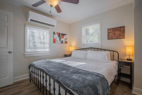 a bedroom with a bed with two night stands and two windows at Caras Cottage - 2 miles from Sanford Stadium in Athens