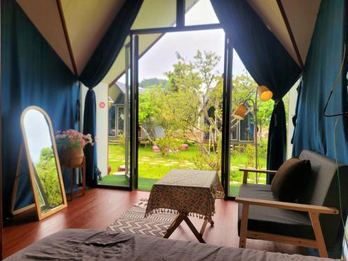 a room with a bed and a large window at Homstay Mimosa Mộc Châu in Mộc Châu