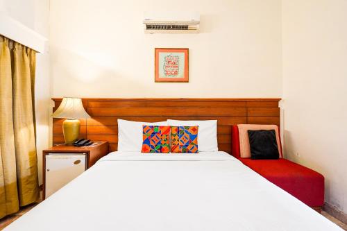 a bedroom with a white bed and a red chair at FabHotel The Dayal - 24 kms from Delhi Gate, 5 kms from Agra Fort in Agra