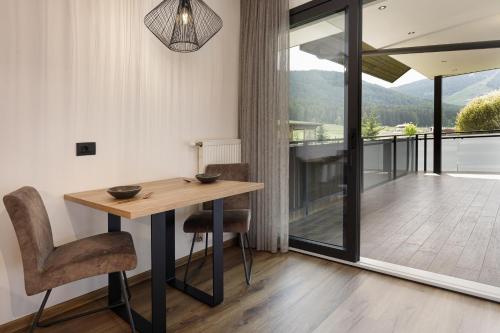 a dining room with a table and chairs and a balcony at Aparthotel Familiaris - Family Apartments - Pools & Spa in Dolomites in Valdaora