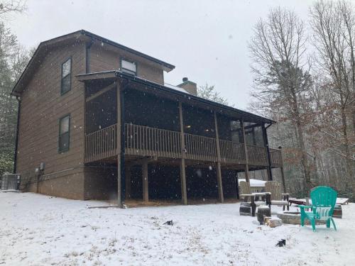 a large house with a deck in the snow at The Cabin Kingdom Hot tub Fire Pit in Blairsville