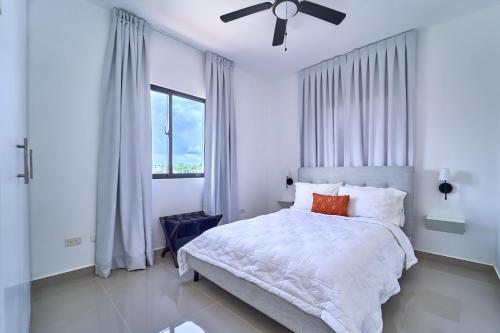 a white bedroom with a bed and a ceiling fan at Cozy Nest in La Romana