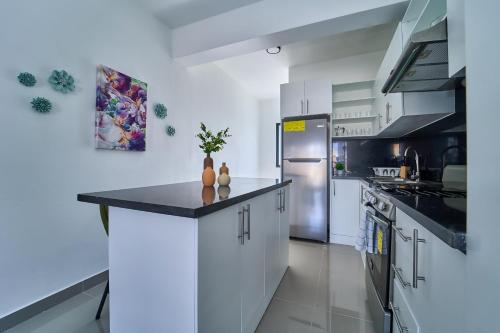 a large kitchen with white cabinets and a refrigerator at Cozy Nest in La Romana