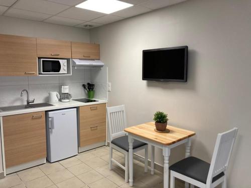 une cuisine avec une table et une télévision au mur dans l'établissement L'escapade, à La Celle-sous-Gouzon