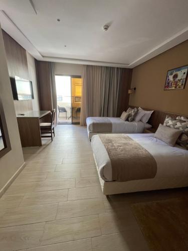 a hotel room with two beds and a desk at Hotel De Nice in Meknès
