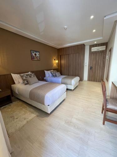 a hotel room with two beds and a chair at Hotel De Nice in Meknès