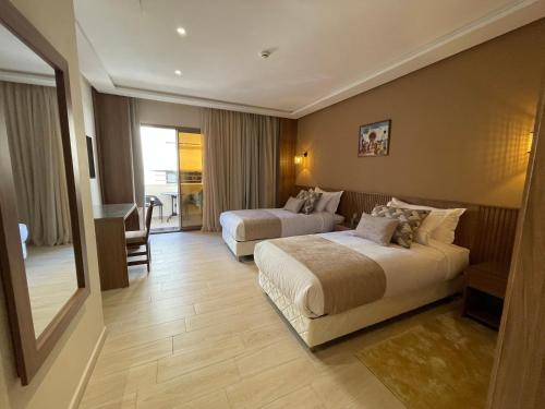 a hotel room with two beds and a television at Hotel De Nice in Meknès