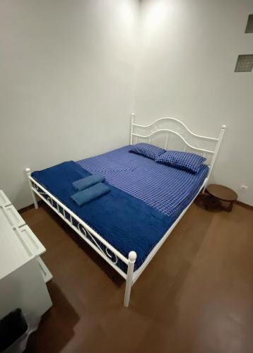 a white bed with blue sheets and pillows on it at D' Jati Homestay in Ungasan