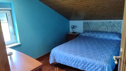 a blue bedroom with a bed and a window at Casa de Aldea Quintana in Quintana