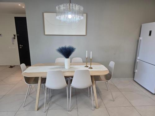 a dining room table with white chairs and a white refrigerator at Briza in Netanya
