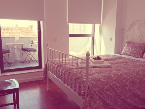 a bedroom with a bed and a balcony with a table at Casa dos Pátios II in Aveiro