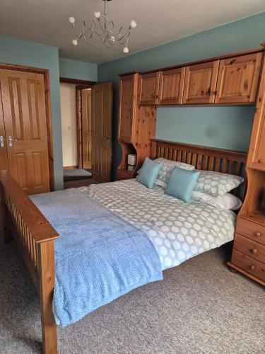 a bedroom with a large bed and wooden cabinets at The Yard Bungalow in Sanquhar