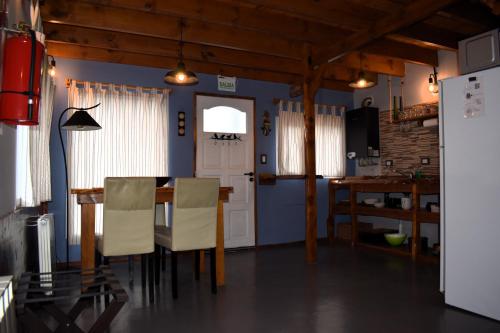 una sala da pranzo con tavolo, sedie e una porta di Cabaña La Marilena, para 2 huespedes con desayuno a El Calafate