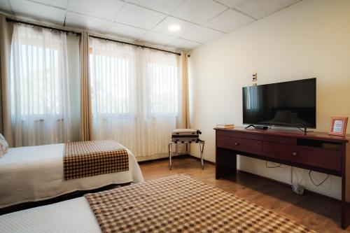 a hotel room with a bed and a flat screen tv at Tur Hotel Santiago in Santiago