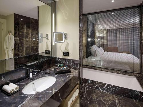 un bagno con un lavandino e un grande specchio di Pullman Istanbul Hotel & Convention Center a Istanbul