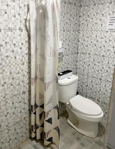 a bathroom with a toilet and a shower curtain at D' Jati Homestay in Ungasan